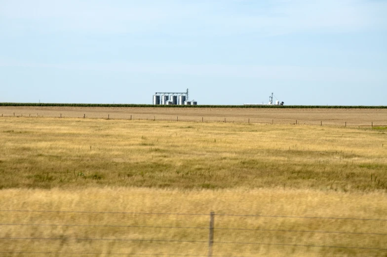 an grain factory on a farm behind a fence