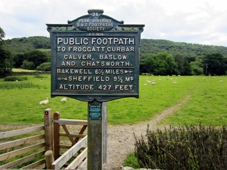 a wooden sign sitting on top of a lush green field