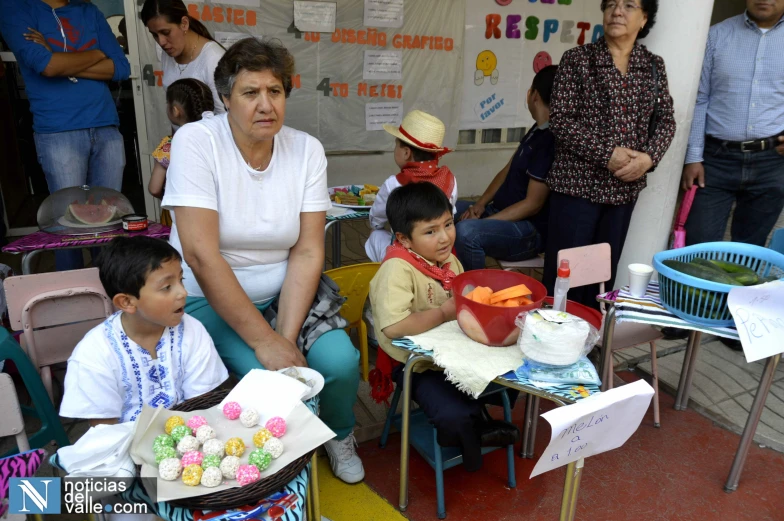 people sitting at tables and chairs with a woman standing behind them