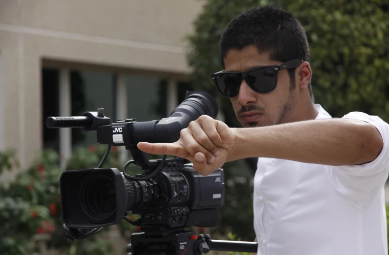 a man standing next to a camera pointing at soing