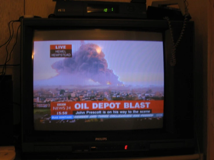 a television with an old, rusted out oil depot blast on the screen