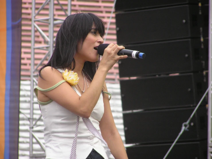 a woman in white clothes standing on stage holding a microphone