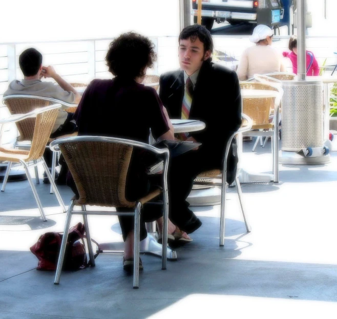 two people sitting next to each other in chairs on a sidewalk