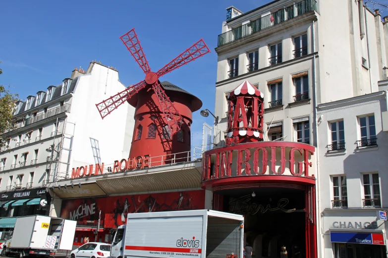 a very large red windmill mounted to the side of a building