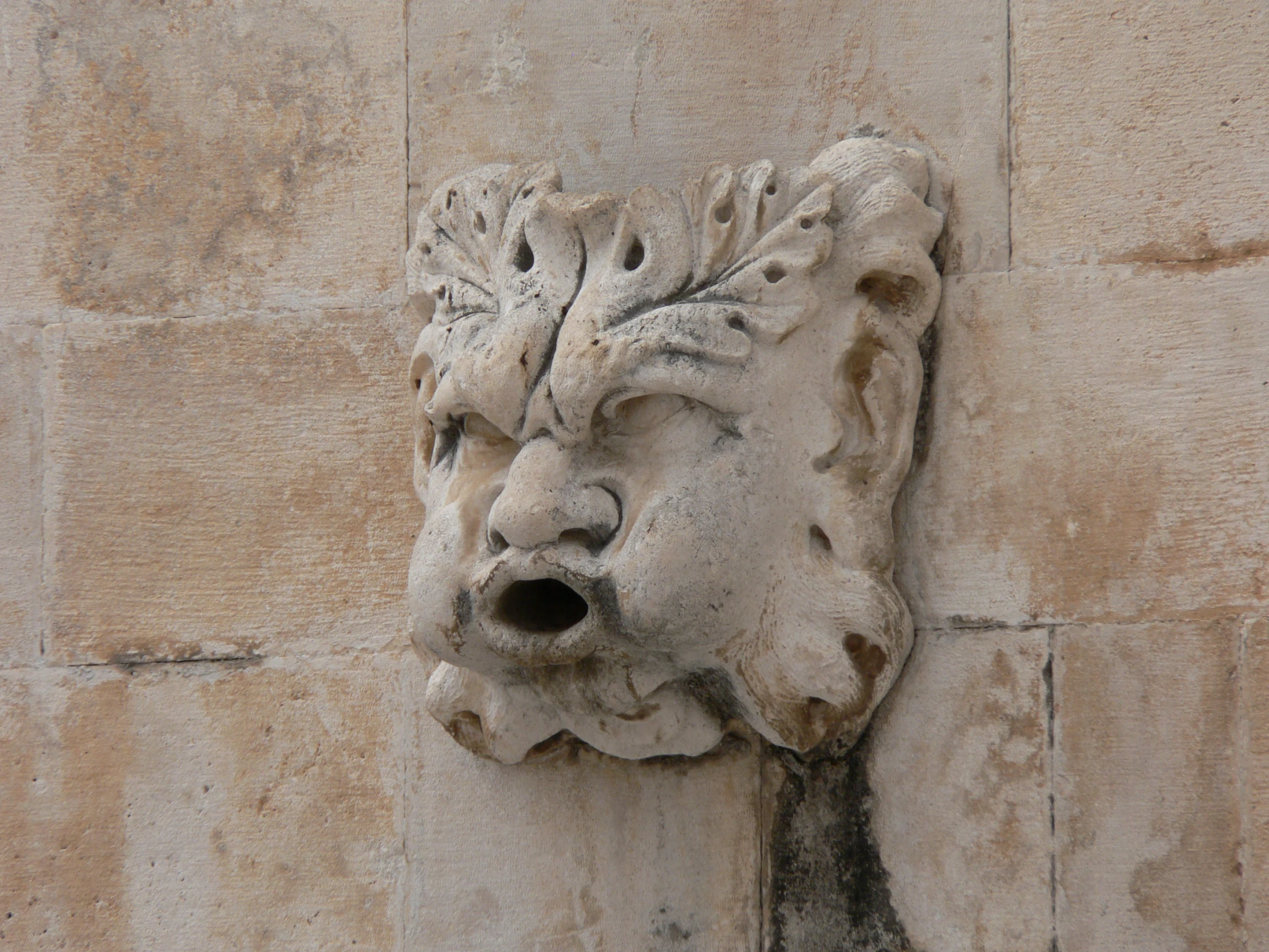 an animal heads on a stone wall mounted to the side of a building