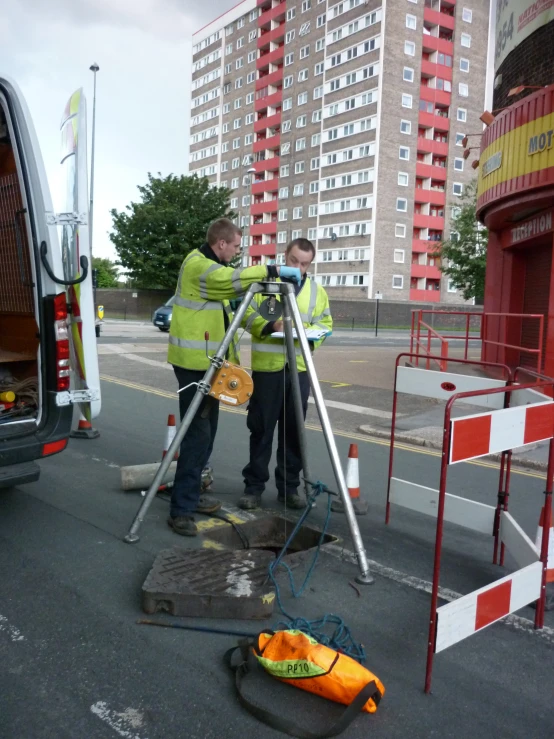 two workers are taking pictures in front of a bus