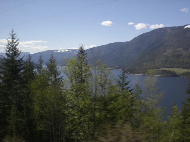 a mountain lake with trees in the foreground and a body of water behind it