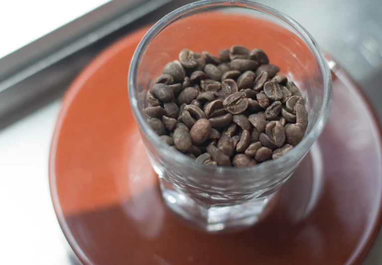 a glass with coffee beans inside of it on top of a table