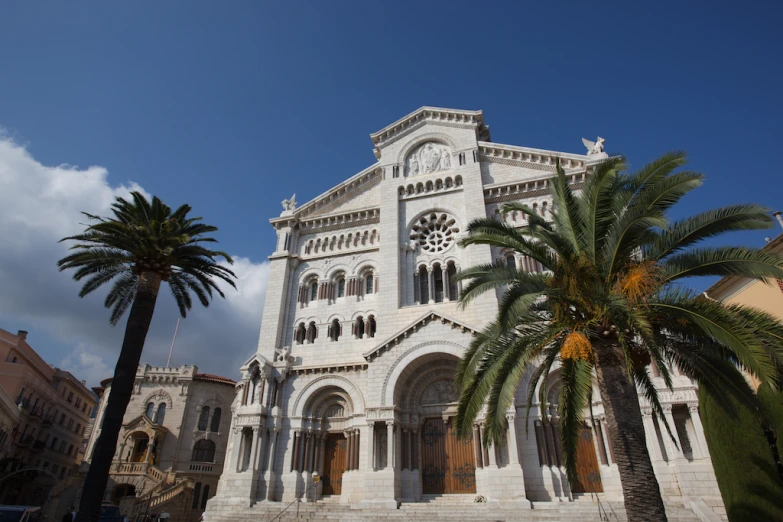 a tall white building with palm trees in front