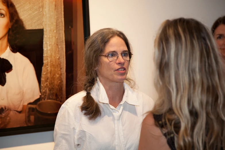 woman speaking to others in front of a painting