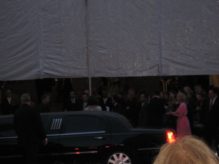 a large group of people are gathered next to the limo