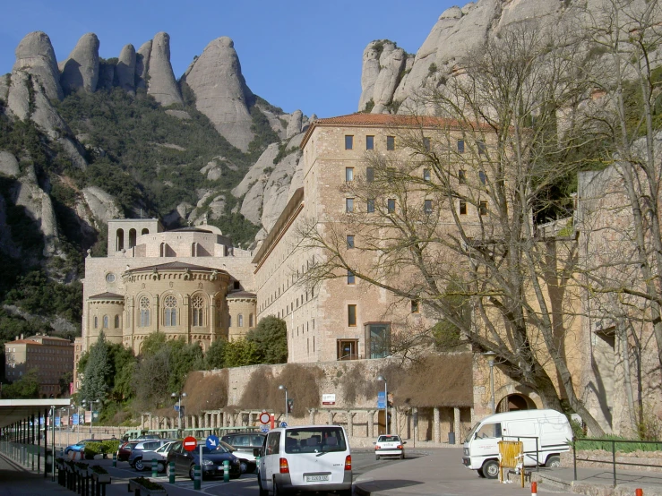 cars are driving in front of mountains with buildings