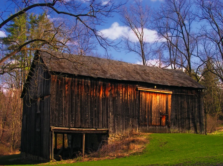 a wooden building next to a lush green field