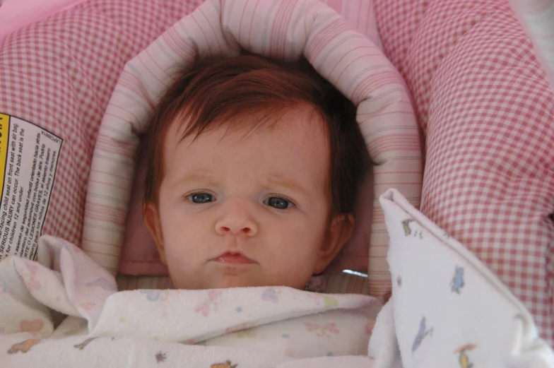 a baby in a pink car seat with a bottle