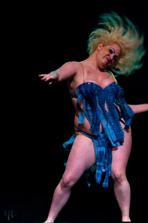 an attractive lady with a wig dances on stage