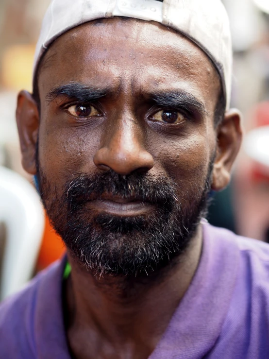 a man with a cap on and a purple shirt