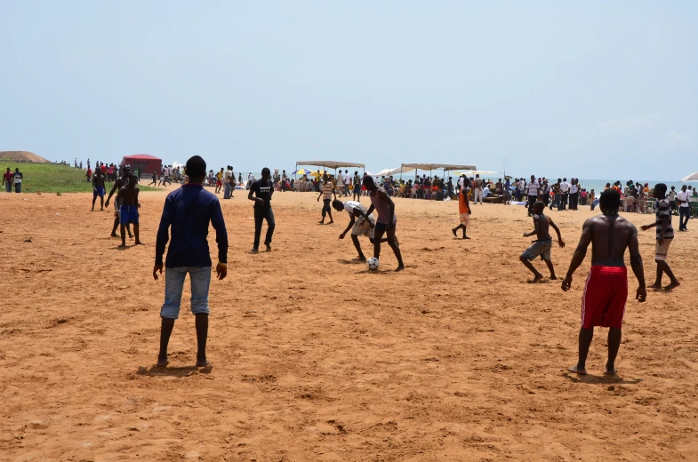 group of people playing soccer on the beach