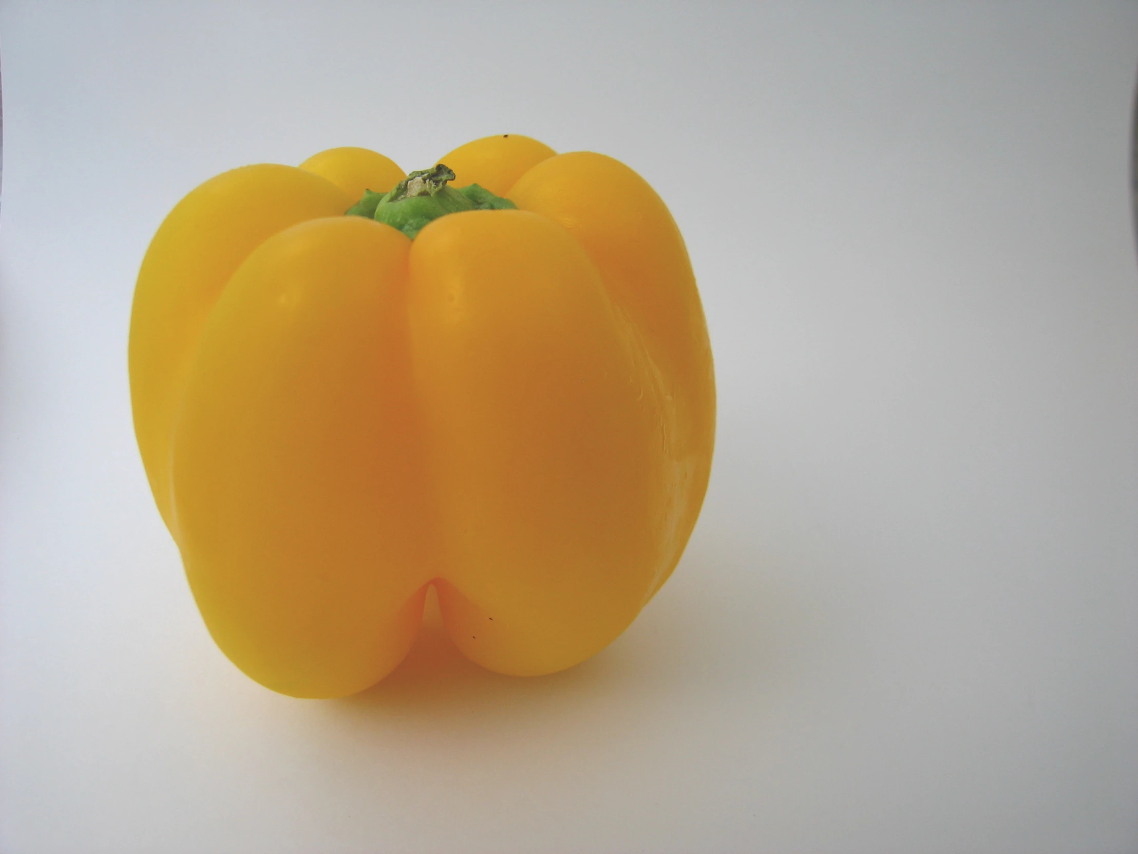 a small group of yellow peppers on a white table