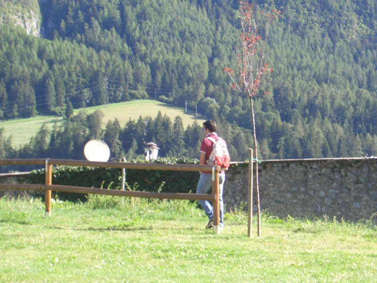 there is a man standing behind a fence and looking up at mountains