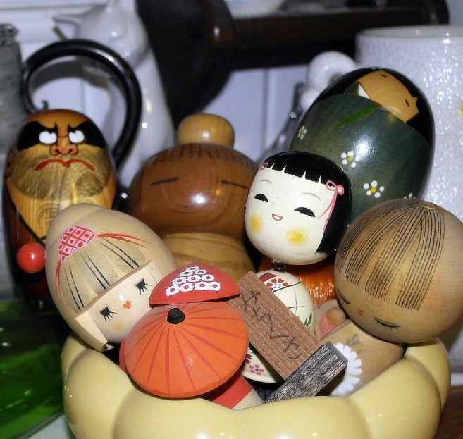 wooden peg dolls and other asian doll ornaments in a bowl