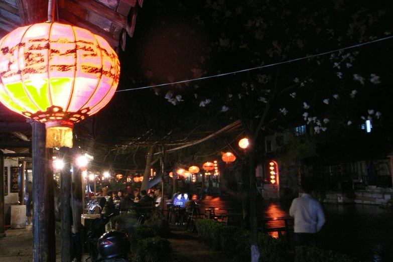 people gathered at night under a large lamp with asian writing