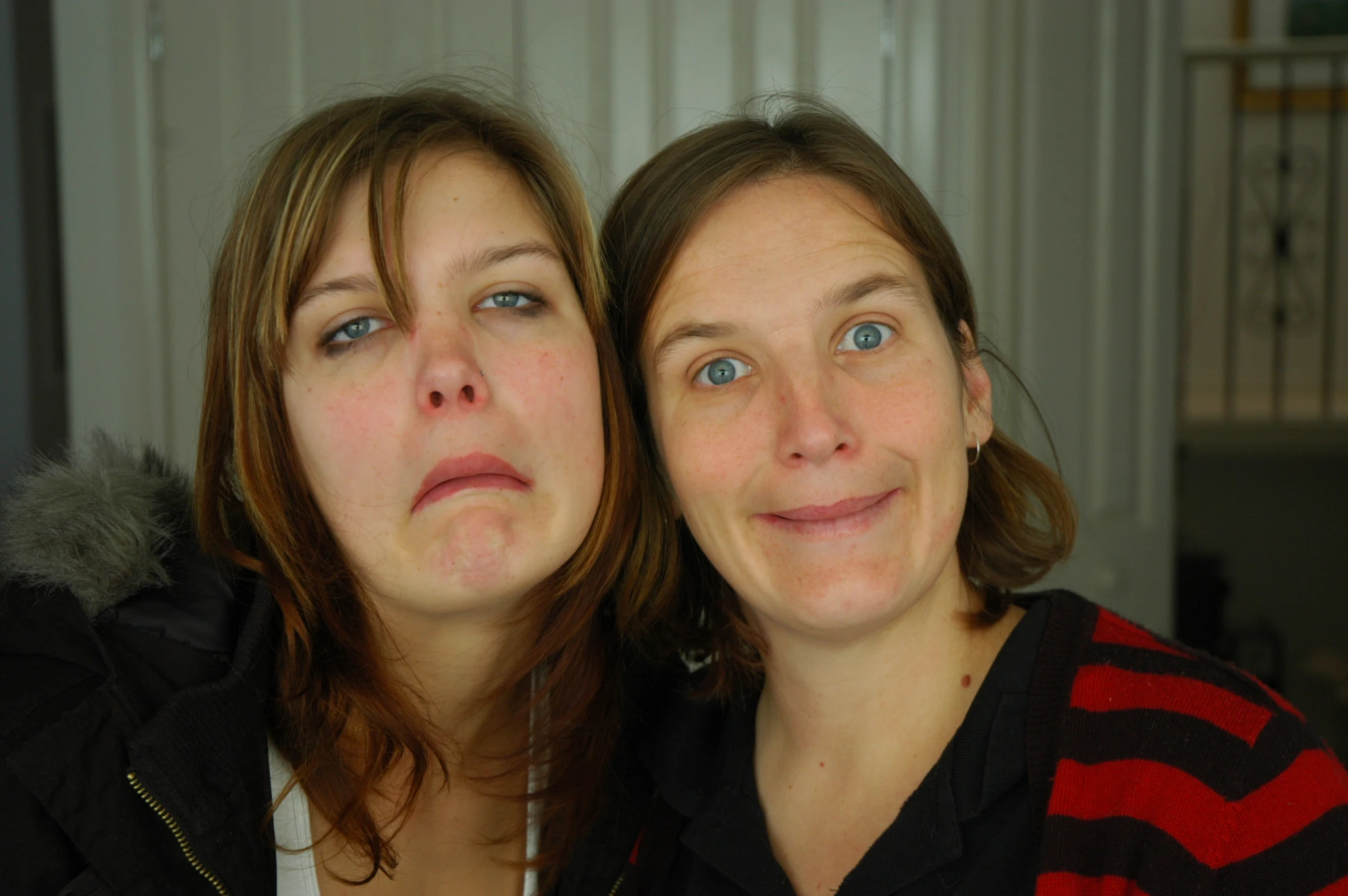 two women with closed mouths stand beside each other