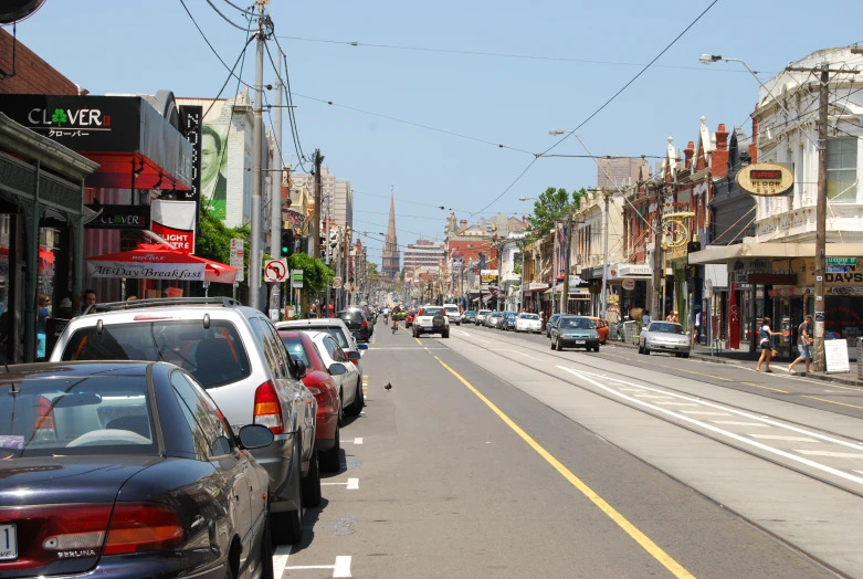 cars are lined up on the street as people walk by