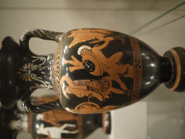 a brown vase with black designs on it