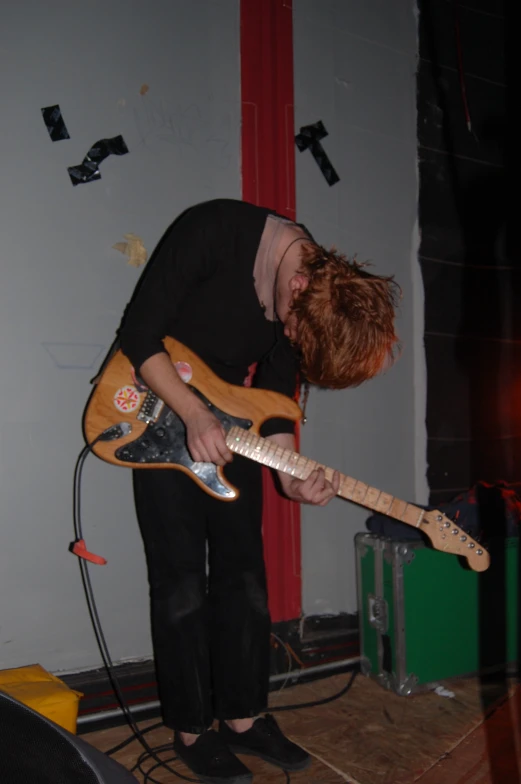 a red headed boy is playing an electric guitar