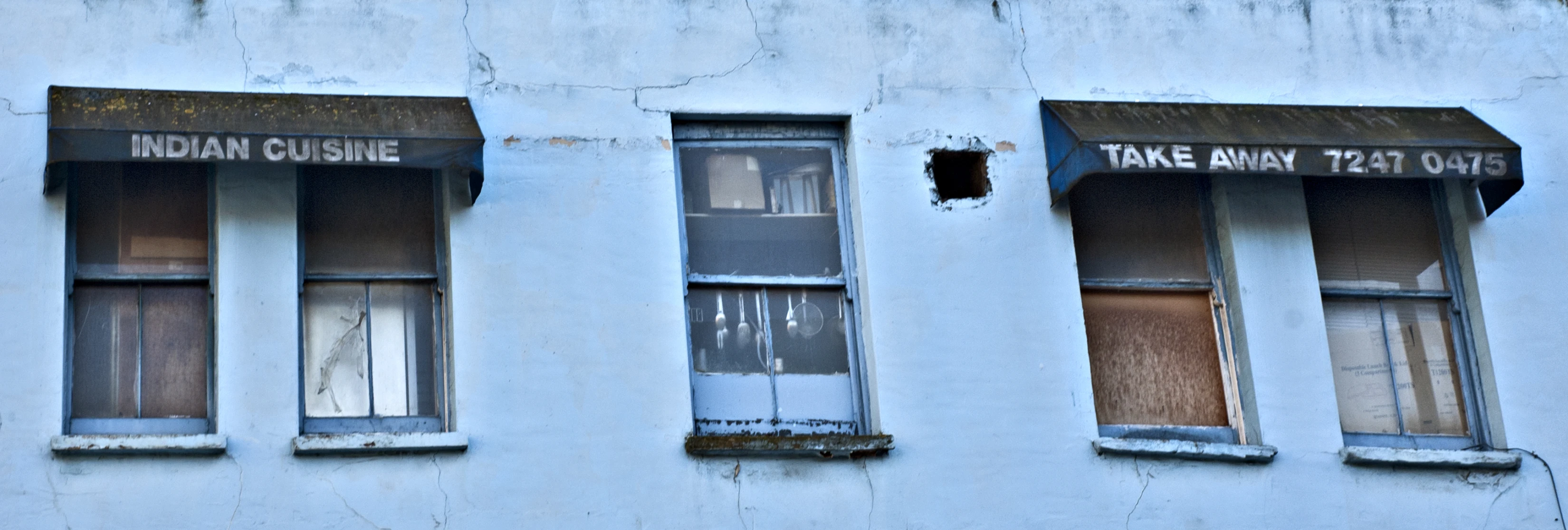 three windows and two curtained doors in an old building