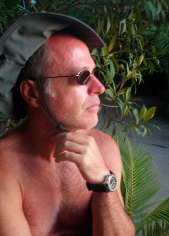 a man is sitting outdoors wearing a hat