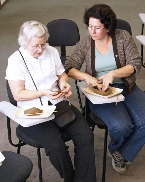 two elderly women are making homemade handmade bowls