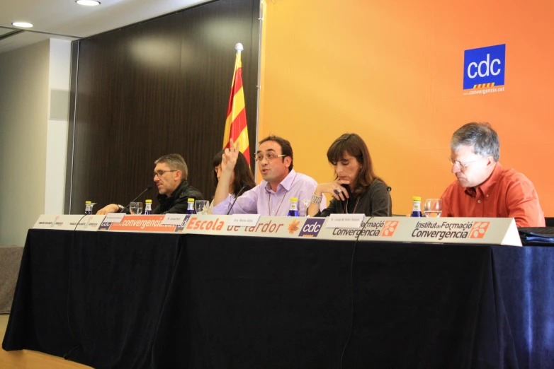 a group of people sitting around a table holding a sign