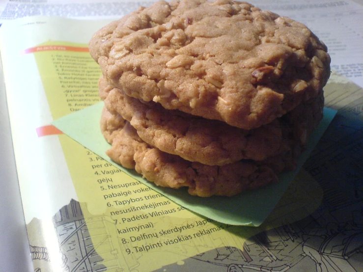 three chocolate chip cookies stacked on a green piece of paper