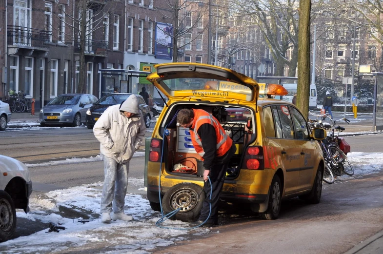 a small yellow car with passengers is parked on the street