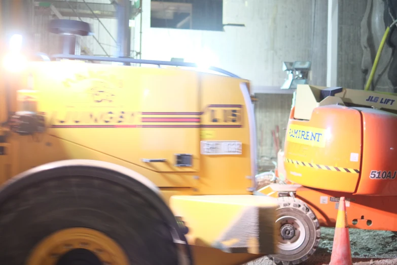 a pair of road work machines parked in a warehouse
