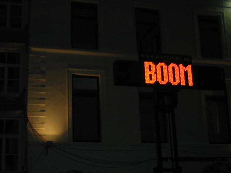 a red sign that reads booom on it in front of a large building
