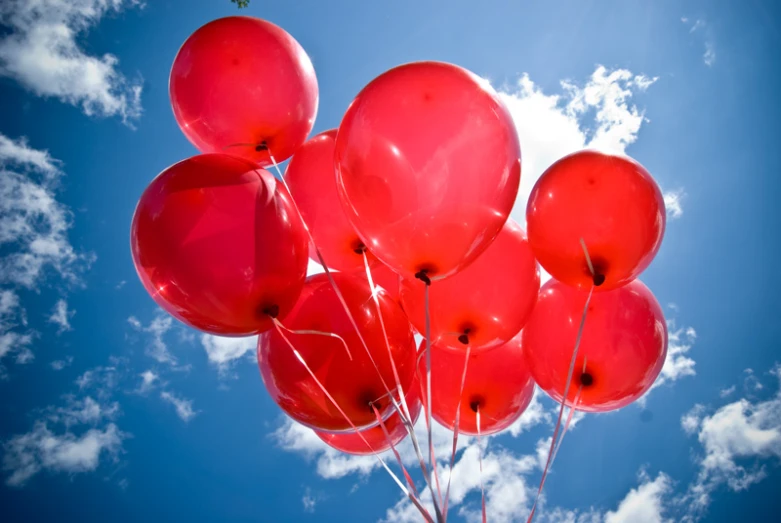 a bunch of red balloons floating through the air