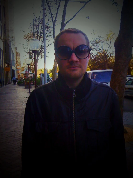 a man in black jacket wearing sunglasses on sidewalk