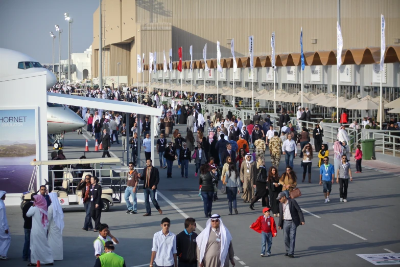 a crowd of people walking on top of a tarmac