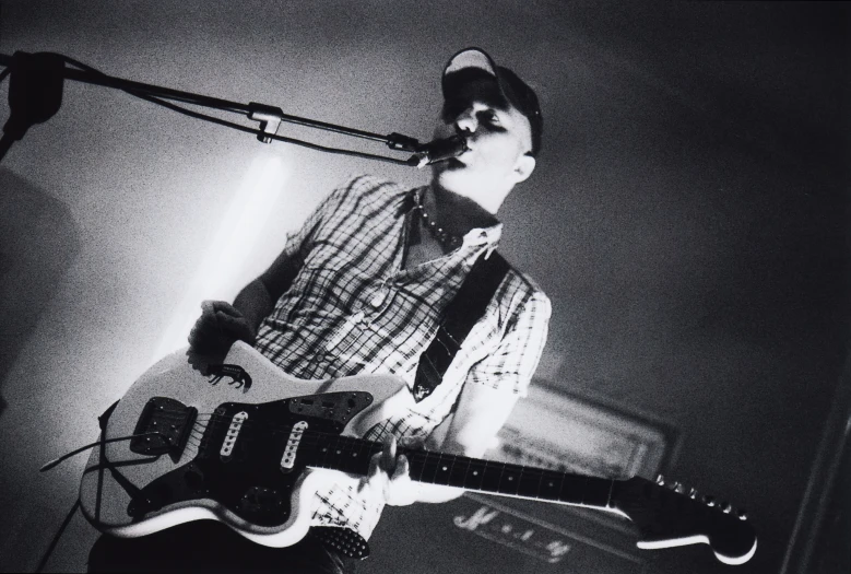 a man is playing a guitar while standing in front of the microphone