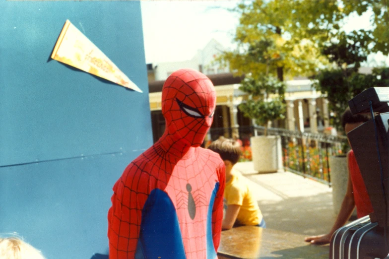 a spider man in a suit stands next to some people