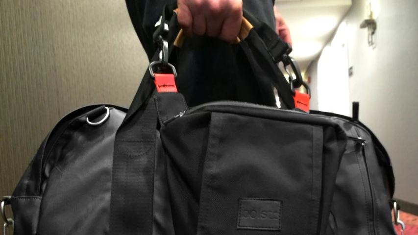a person holds onto a black duffle bag