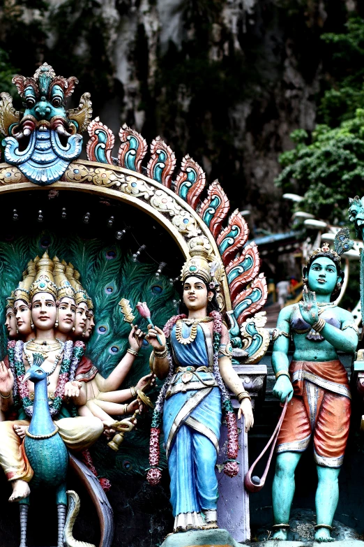 various statues in an open area with mountains behind them