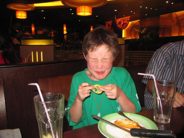 boy eating donut with green shirt at a table
