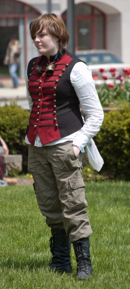 a woman standing in the grass wearing an odd looking jacket