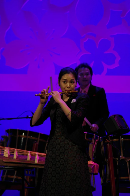 a woman in black dress holding scissors in front of a microphone