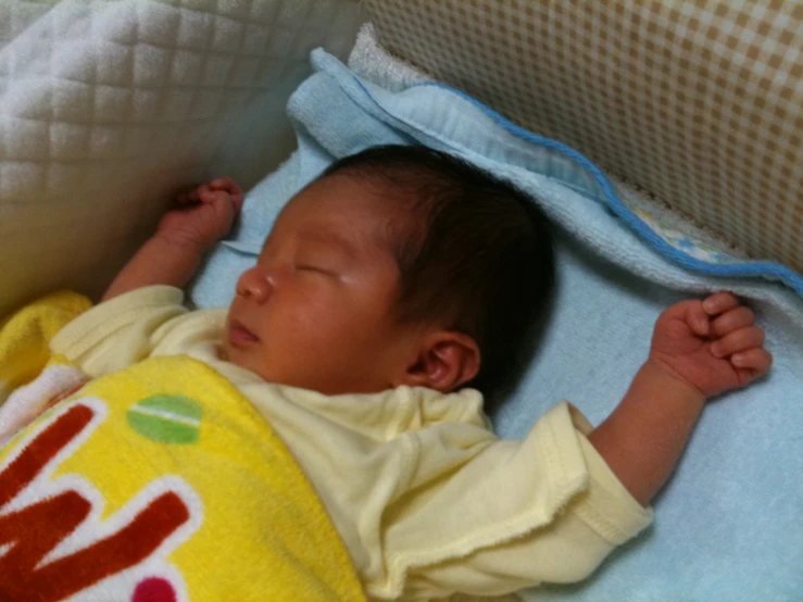 a newborn infant is laying in the crib with its head tucked up