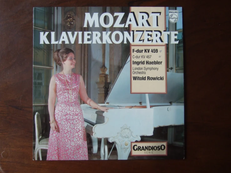 a woman in pink dress standing near a piano