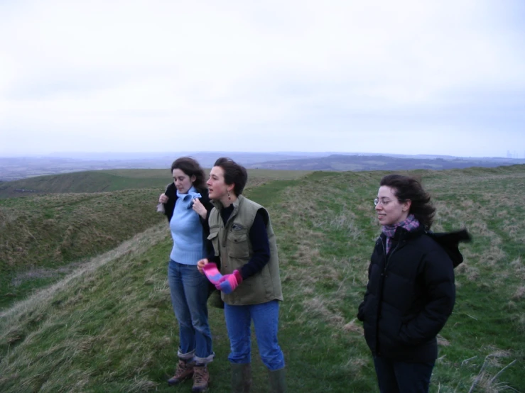 three women standing on a hill and looking into the distance